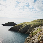 People walking on coastal path towards a lighthouse