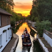 People travelling on a narrow boat at sunset
