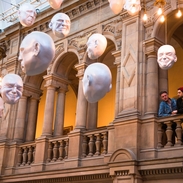 Deux hommes regardant une installation de sculptures de têtes suspendues