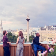 People having a drink at a rooftop bar under a grey sky