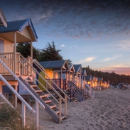 Sonnenuntergang bei Flut hinter den alten Strandhütten an der Küste