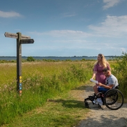 A man who uses a wheelchair and a woman review a map in the countryside