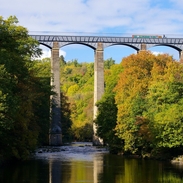 A tall aqueduct spanning a pretty stream.