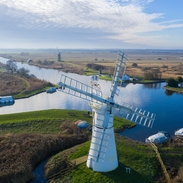 Aerial view of a windmill and surrounding pasture and canals 