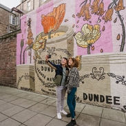A man and a woman taking a selfie in front of the marmalade mural.