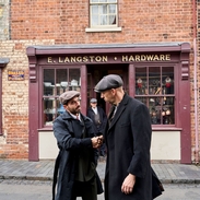 Two men shaking hands on the street in front a hardware shop at a living museum