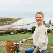 Lächelnde Frau auf dem Fahrrad mit weißen Klippen im Hintergrund