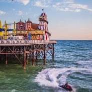 Jetski in sea below a seaside pier with a funfair