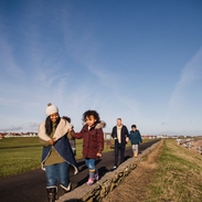 Family and friends walking along a coastal path in the winter sunshine