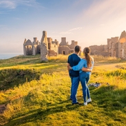 A couple enjoying the views of a castle remains at golden hour. 