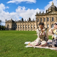 Two women enjoy scone with jam and cream in the garden of a heritage property