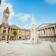 Historical building, with a clock tower, beside a fountain