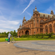 A cyclist parked out the front of an ornate Art Gallery and Museum.