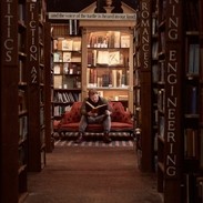 Mann sitzt auf einem Sofa und liest ein Buch in einer Buchhandlung