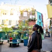 Female tourist exploring a London shopping courtyard with shops and outdoor seating.