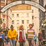One young woman and two young men, walking down a street