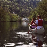 Two people canoeing along a river 