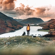 Rear view of young woman on a hillside with two dogs