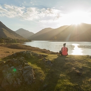 Woman, meditating in green valleys, near lake. High sun
