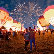 Lit up hot air balloons and fireworks in the night sky