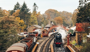 Steam train on train tracks and old-fashioned carriages at Goathland Railway Station