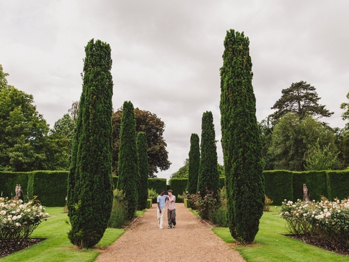 Two young men walk through ornate gardens